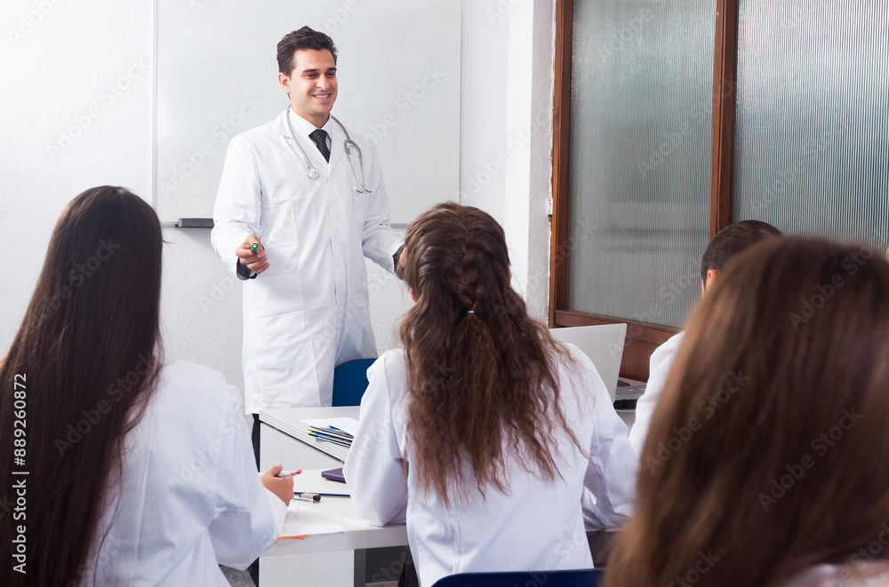 Fototapeta premium Students in white coats listen to lecture in audience