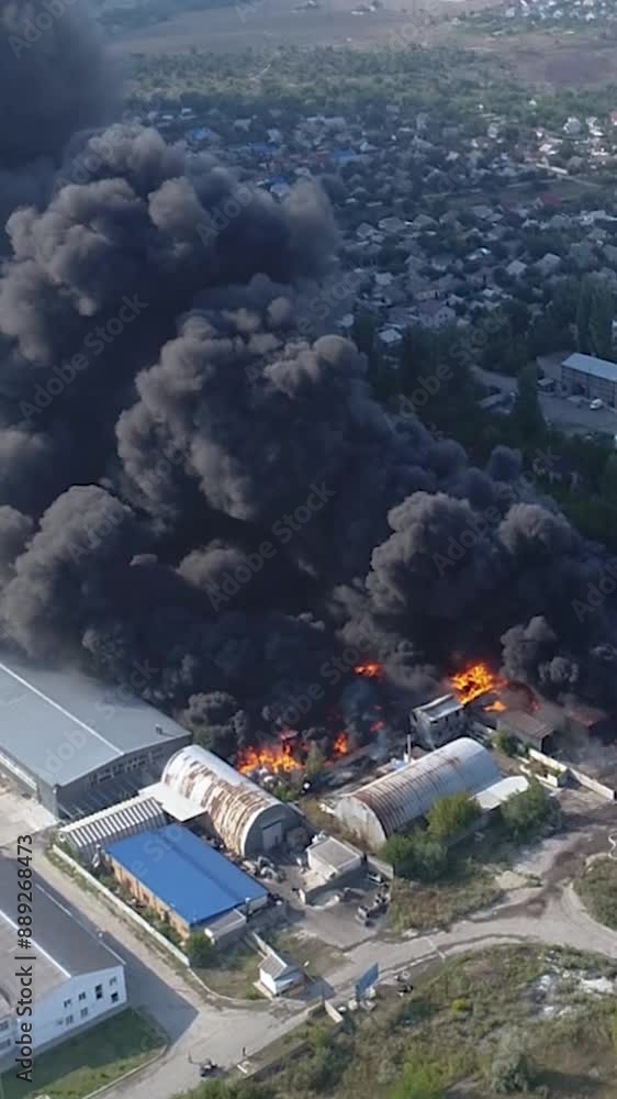 Drone video of a large fire warehouse. Thick black smoke in the sky. The factory is on fire. Warehouse industrial hangar. Rescuers are putting out a strong fire. View from above. Vertical video. Drone video of a large fire warehouse. Thick black smoke in the sky. The factory is on fire. Warehouse industrial hangar. Rescuers are putting out a strong fire. View from above. Vertical video.