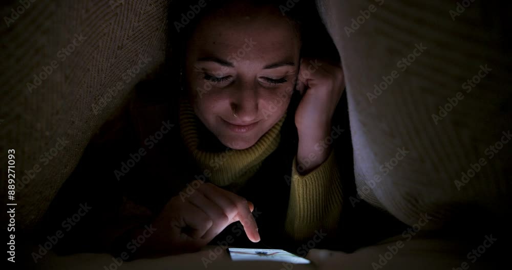 Woman lying on the bed under the blanket and using smartphone navigating on social media Woman lying on the bed under the blanket and using smartphone navigating on social media