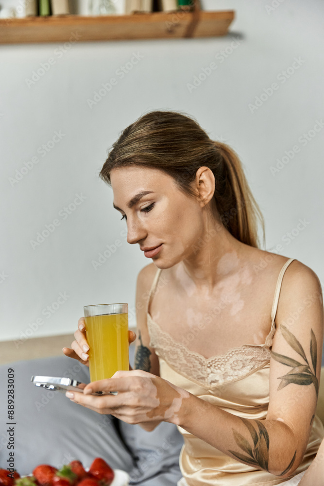 A young woman with vitiligo and a tattoo sits in her cozy bedroom, enjoying a glass of juice while checking her phone. A young woman with vitiligo and a tattoo sits in her cozy bedroom, enjoying a glass of juice while checking her phone.