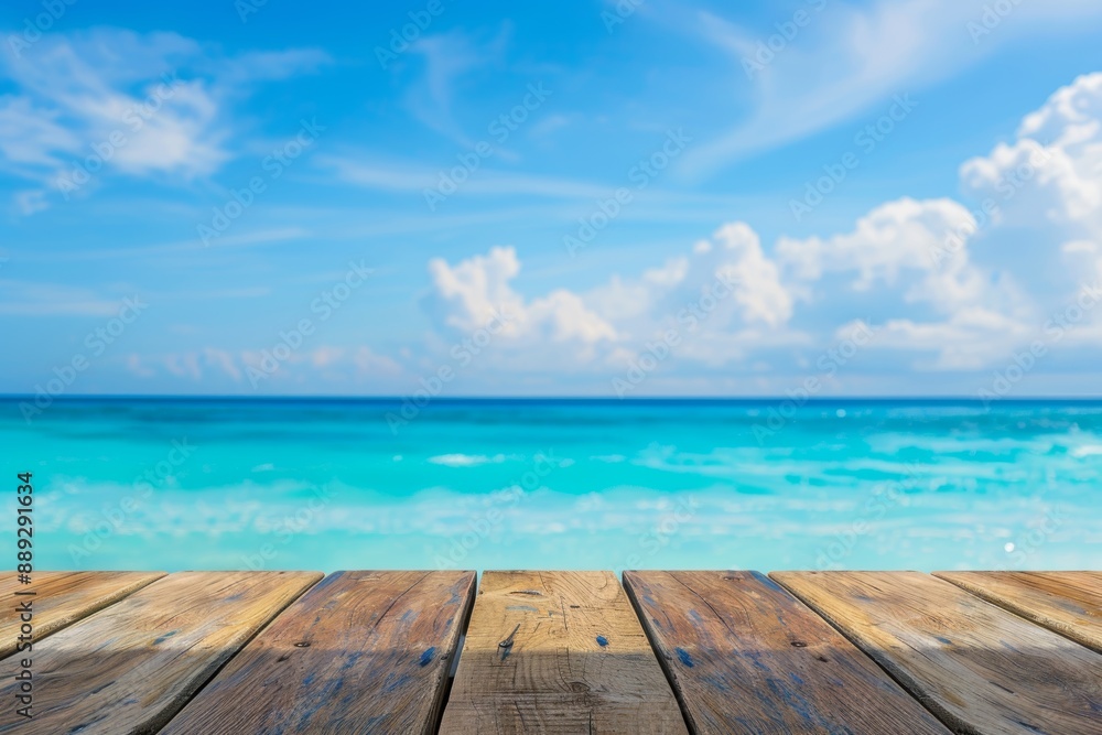 Fototapeta premium An image of a wood table top against a blurry background of sparkling sea water and summer skies