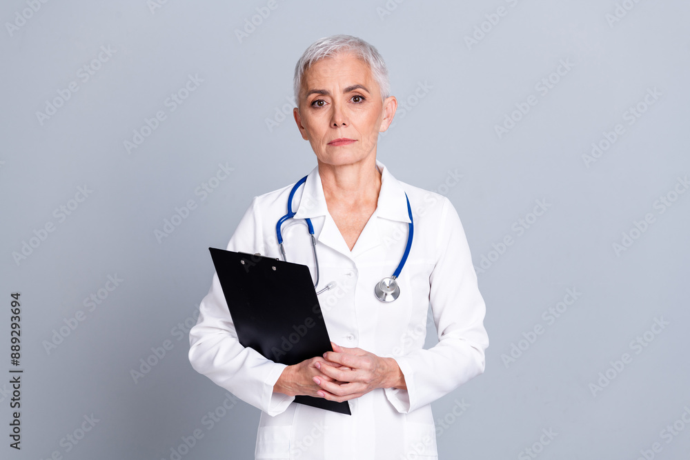 Photo of pretty retired female clinic professional doctor hold paperholder wear white robe uniform isolated on gray color background Photo of pretty retired female clinic professional doctor hold paperholder wear white robe uniform isolated on gray color background