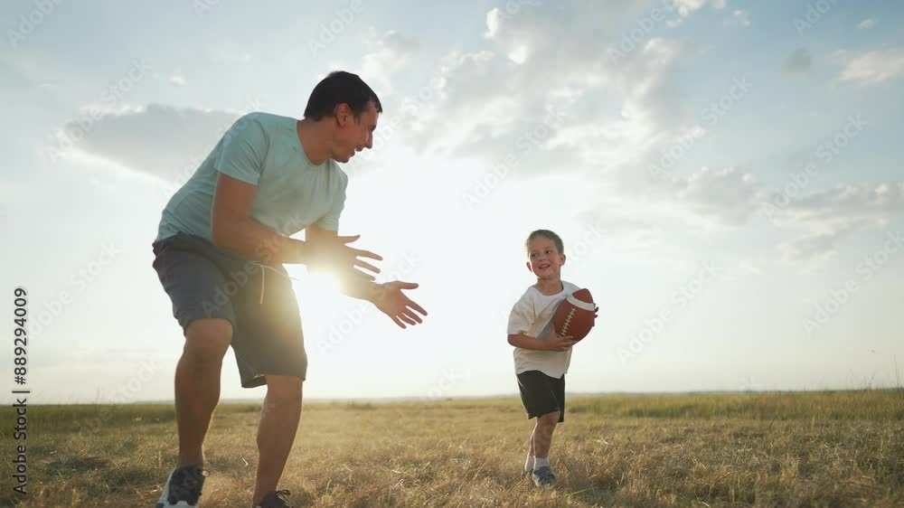 Happy family plays rugby. Father son enjoying sunny day. Boy learning to play rugby with father help. Family bonding through sport. family lifestyle rugby ball game. Family play rugby ball bonding fun Happy family plays rugby. Father son enjoying sunny day. Boy learning to play rugby with father help. Family bonding through sport. family lifestyle rugby ball game. Family play rugby ball bonding fun