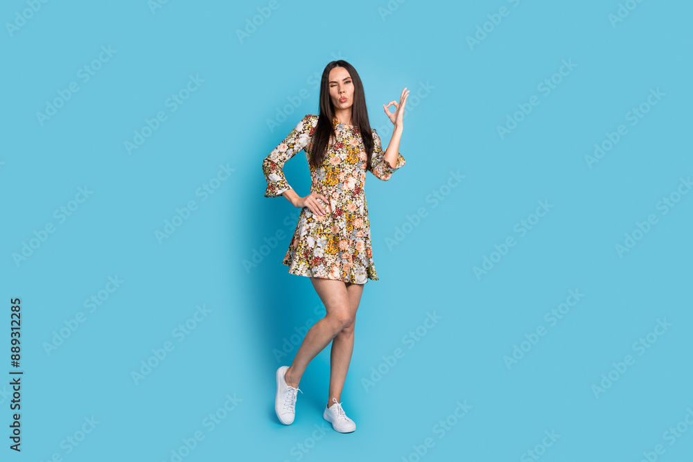 Full length photo of shiny attractive lady dressed floral print outfit showing okey sign empty space isolated blue color background Full length photo of shiny attractive lady dressed floral print outfit showing okey sign empty space isolated blue color background