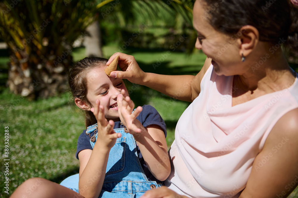 Mother and daughter sharing playful moment outdoors with ice cream cone Mother and daughter sharing playful moment outdoors with ice cream cone