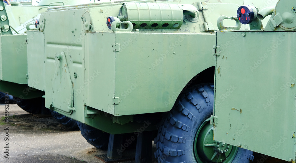 Military Armored Transport Side View. Close-up of a military armored transport vehicle with a focus on its rugged structure and large wheels, painted in green for camouflage and durability. Military Armored Transport Side View. Close-up of a military armored transport vehicle with a focus on its rugged structure and large wheels, painted in green for camouflage and durability.