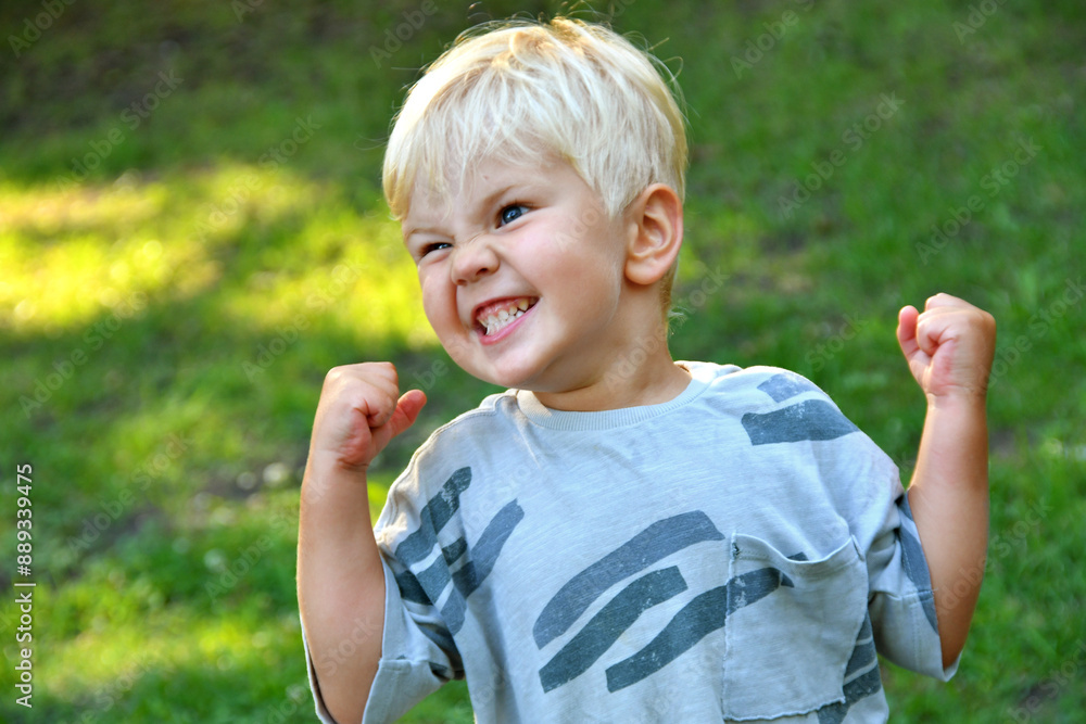 Outdoor Portrait of funny little boy showing his muscles Outdoor Portrait of funny little boy showing his muscles