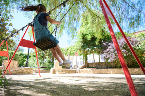 Child swinging on a swing set in a park on a sunny day