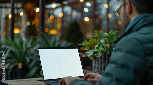 Man using laptop in outdoor seating area of restaurant at night photo