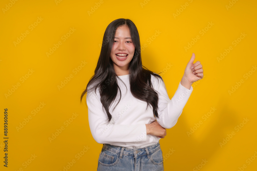 Smiling young woman giving a thumbs up on a bright yellow background, radiating positivity and approval Smiling young woman giving a thumbs up on a bright yellow background, radiating positivity and approval