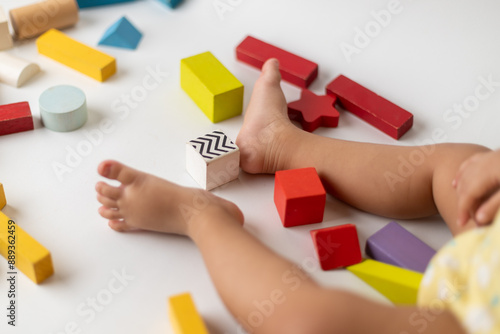 Little girl playing with multi colored wooden block toys, sitting on a white table, top shots, playing hands and feet