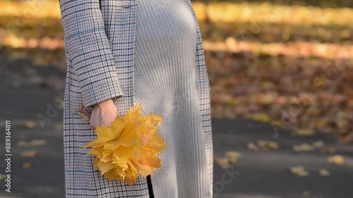 Pregnant woman walking in autumn park. Concept of pregnancy, maternity, expectation for baby birth.
