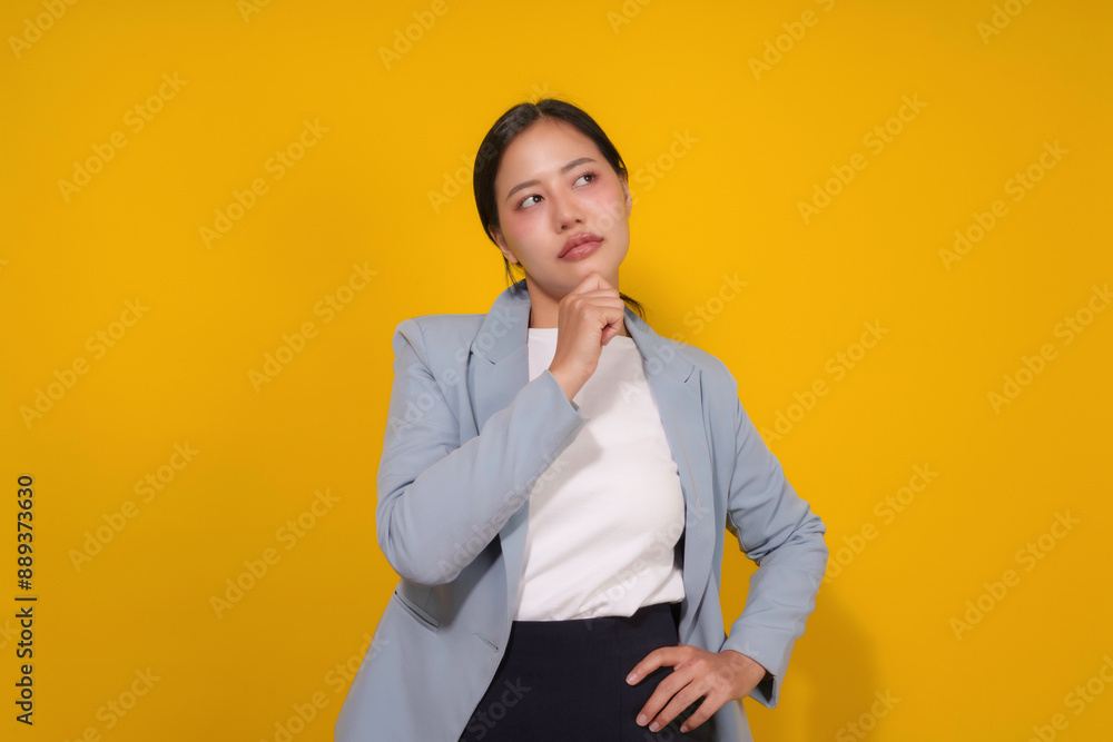 Young businesswoman is deep in thought, her hand resting on her chin as she contemplates a challenge or seeks a solution Young businesswoman is deep in thought, her hand resting on her chin as she contemplates a challenge or seeks a solution