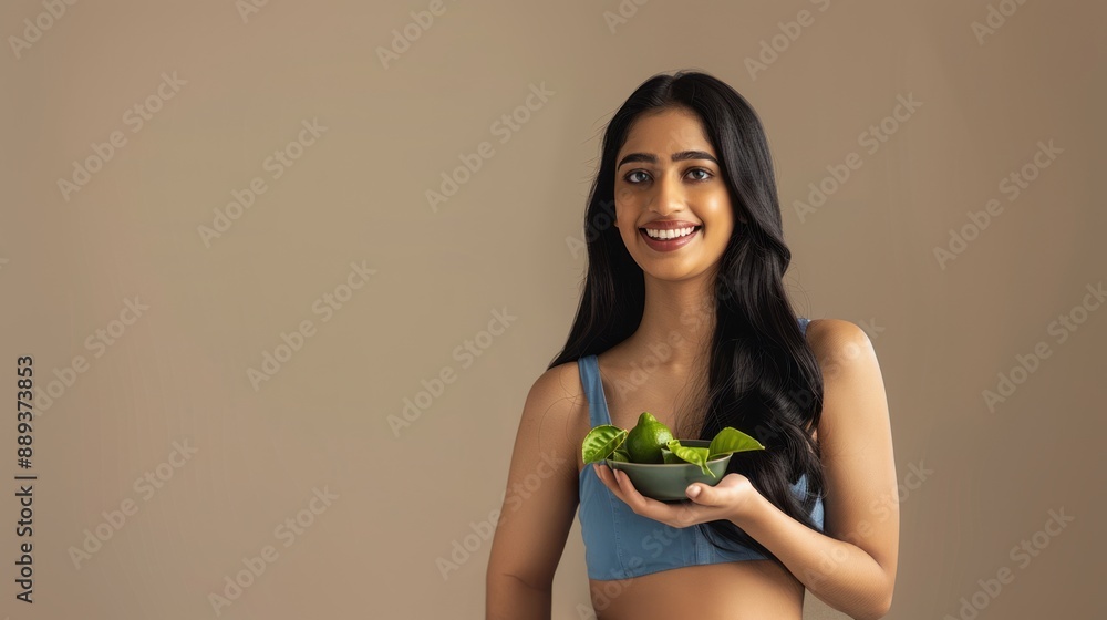 Attractive Indian woman holding a small bowl with lime leaves on beige background, herbal remedy, health benefits, lime leaves, beauty treatment Attractive Indian woman holding a small bowl with lime leaves on beige background, herbal remedy, health benefits, lime leaves, beauty treatment