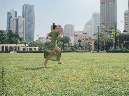 Canvas Print Joyful Woman Running Freely in Urban Park in Kuala Lumpur - Energetic Escape in