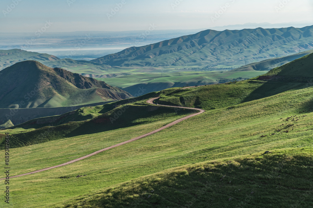 Fototapeta premium Winding mountain road in a green mountain gorge. Nature of Kyrgyzstan. Road to Chon-Kurchak.
