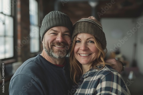 Portrait of a happy caucasian couple in their 40s sporting a trendy beanie isolated in empty modern loft background © CogniLens