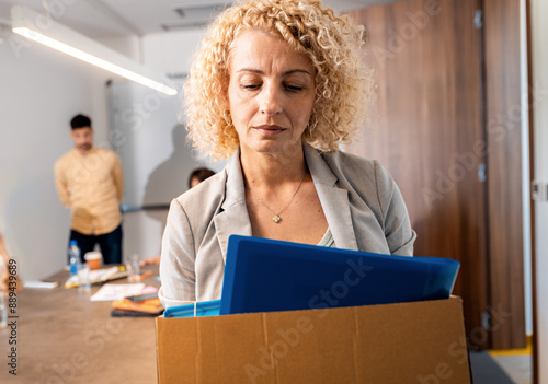 Portrait of woman holding box of personal belongings being fired from work. photo