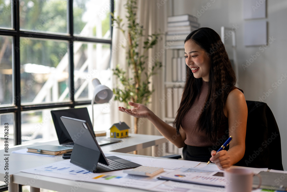 A woman is sitting at a desk with a laptop and a pen A woman is sitting at a desk with a laptop and a pen