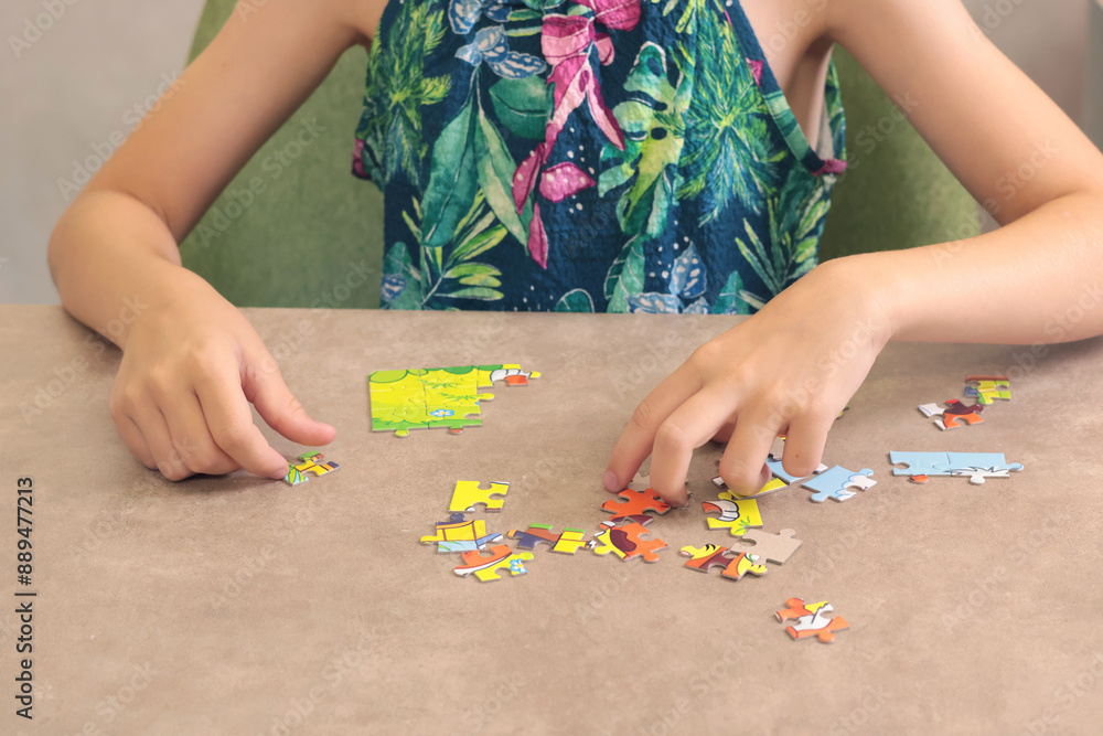 Young teenage girl putting together puzzle on table at home. Toys and activiti for children. Developmental activities at home. Young teenage girl putting together puzzle on table at home. Toys and activiti for children. Developmental activities at home.
