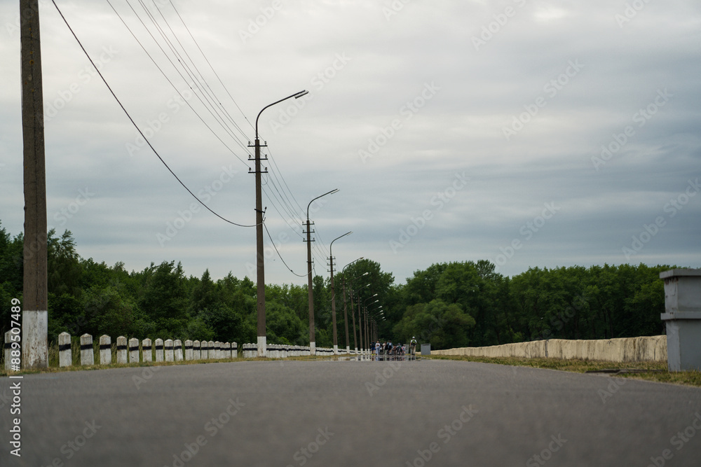 Fototapeta premium The road leading into the distance. The road along the sea where people walk. Lampposts along the road