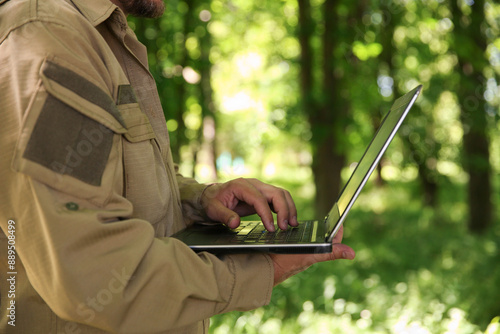 Φωτογραφία Forester with laptop examining plants in forest, closeup