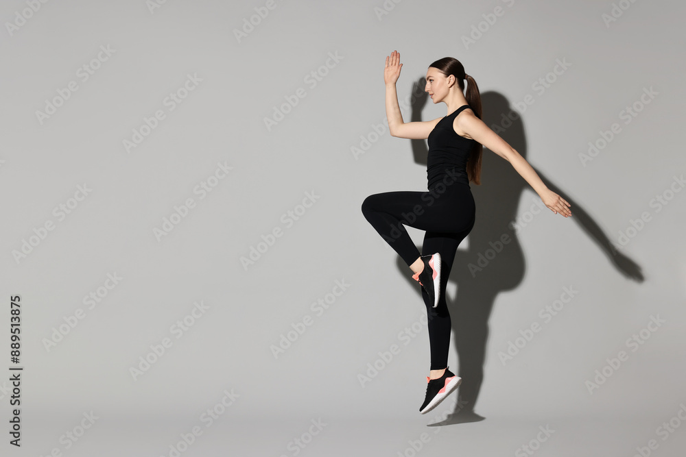 Young woman doing aerobic exercise on light grey background Young woman doing aerobic exercise on light grey background