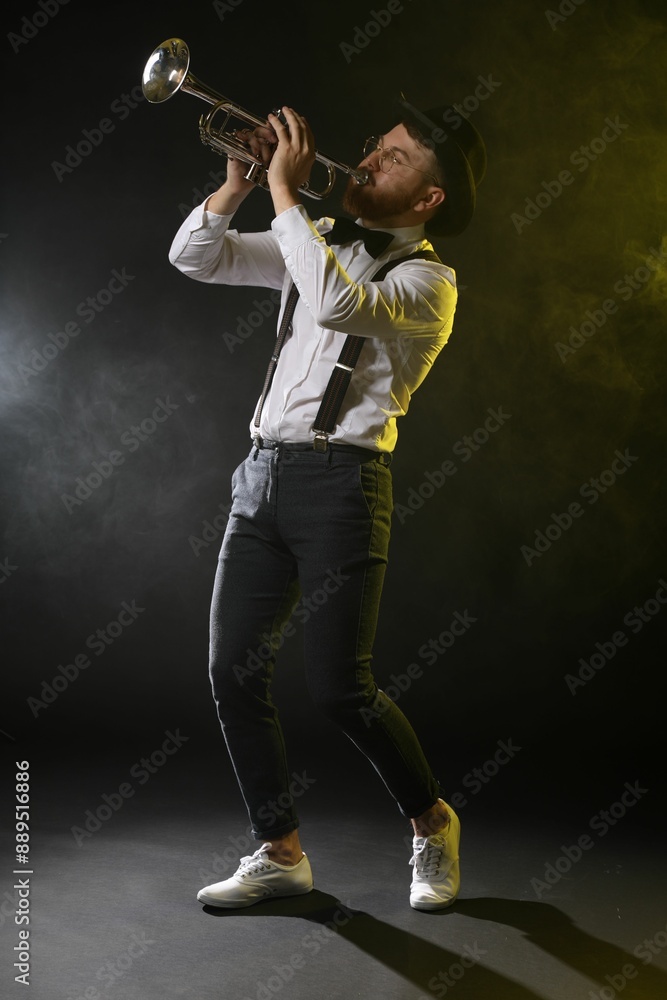 Professional musician playing trumpet on black background in color lights and smoke Professional musician playing trumpet on black background in color lights and smoke