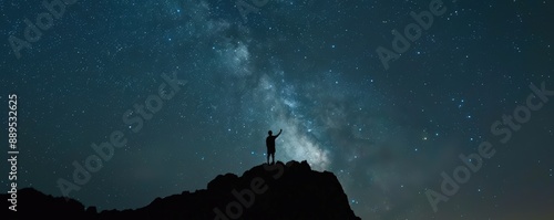 Silhouette of a person on a rock under a stunning Milky Way sky at twilight, capturing the beauty of the stars and universe. photo