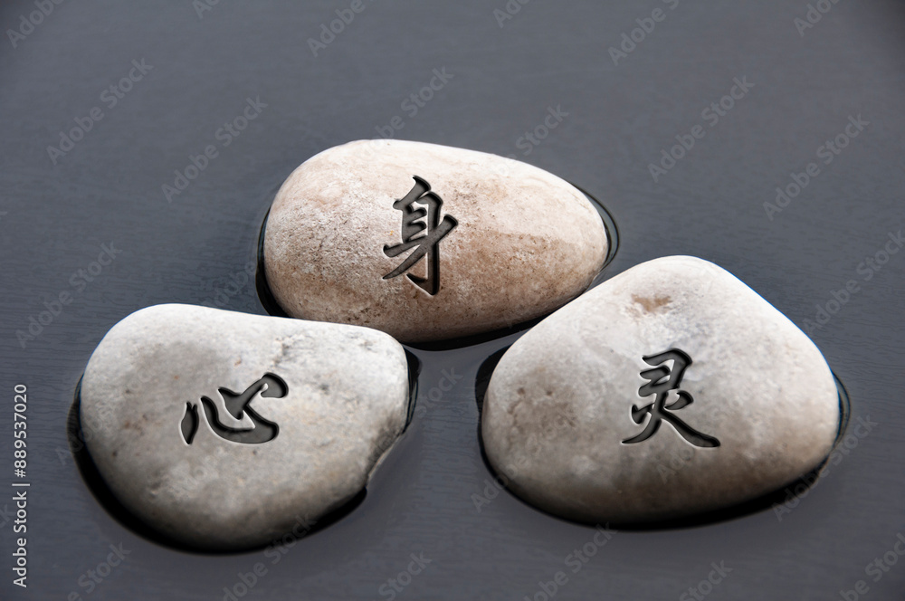 Top view of Chinese character representing body, mind and spirit text engraved on zen stones with water background Top view of Chinese character representing body, mind and spirit text engraved on zen stones with water background