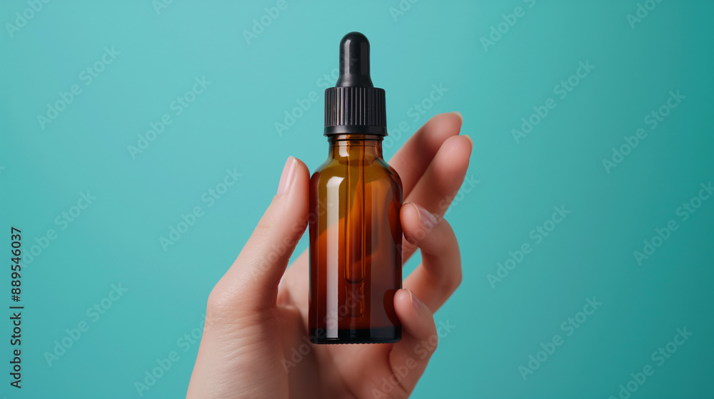 Fototapeta premium Hand Holding Amber Dropper Bottle on Turquoise Background