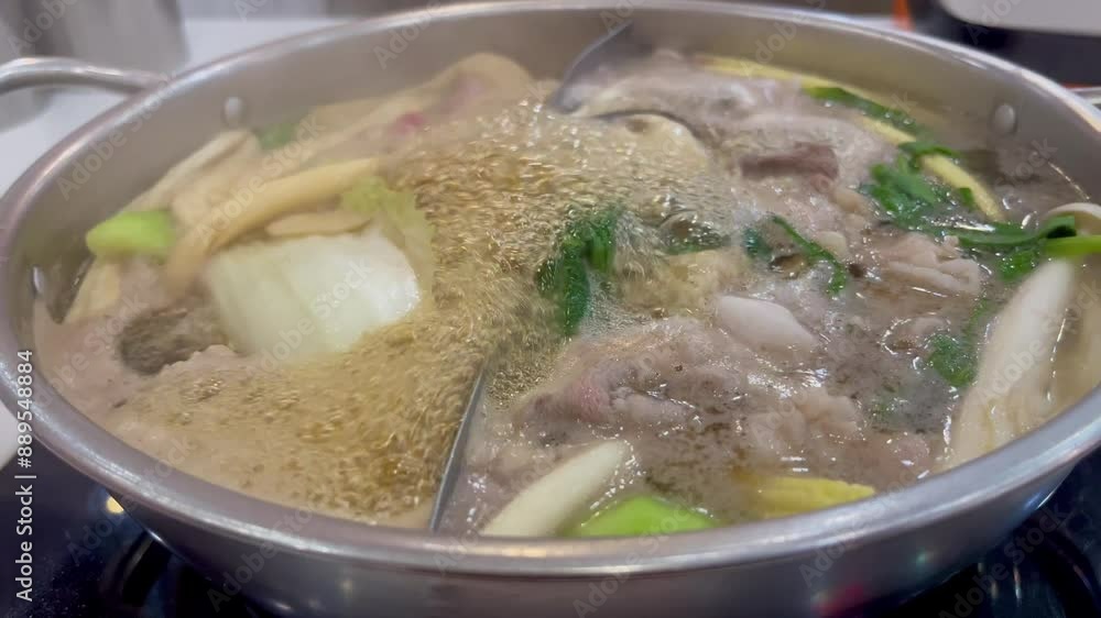 Boiling hot pot with various vegetables, meat, and broth, creating a savory and steaming dish. Boiling hot pot with various vegetables, meat, and broth, creating a savory and steaming dish.