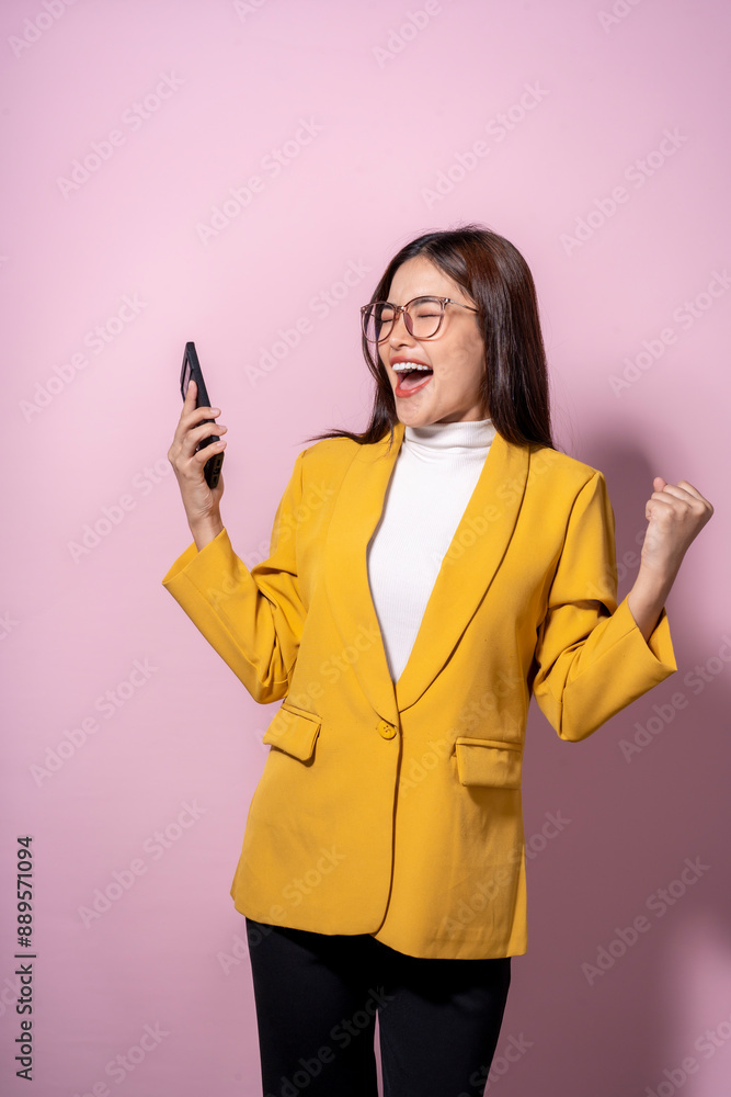 A woman in a yellow jacket is holding a cell phone and smiling A woman in a yellow jacket is holding a cell phone and smiling
