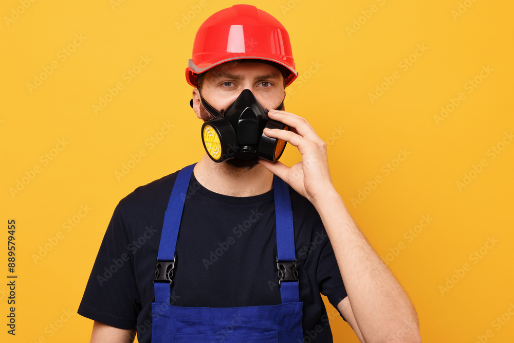 Man in respirator mask and hard hat on yellow background Man in respirator mask and hard hat on yellow background