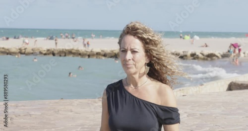 Woman with curly hair walking by the sea
