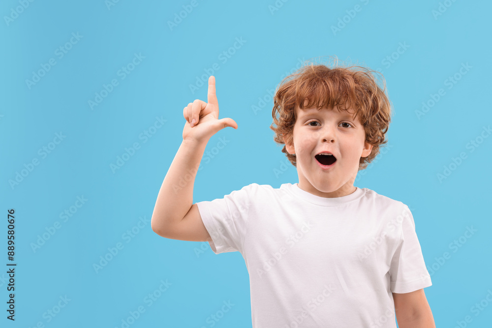 Portrait of emotional little boy pointing at something on light blue background Portrait of emotional little boy pointing at something on light blue background
