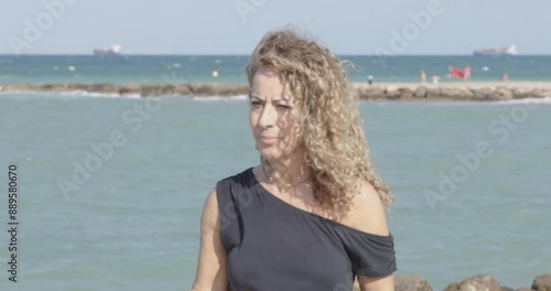 Woman with curly hair walking by the sea
