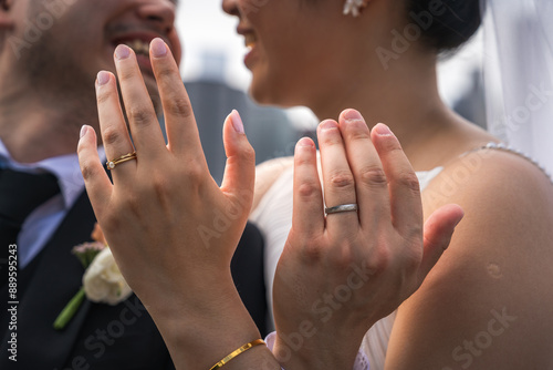 Fotografie A bride and groom hold up and intertwine their hands to show off their rings after their wedding ceremony