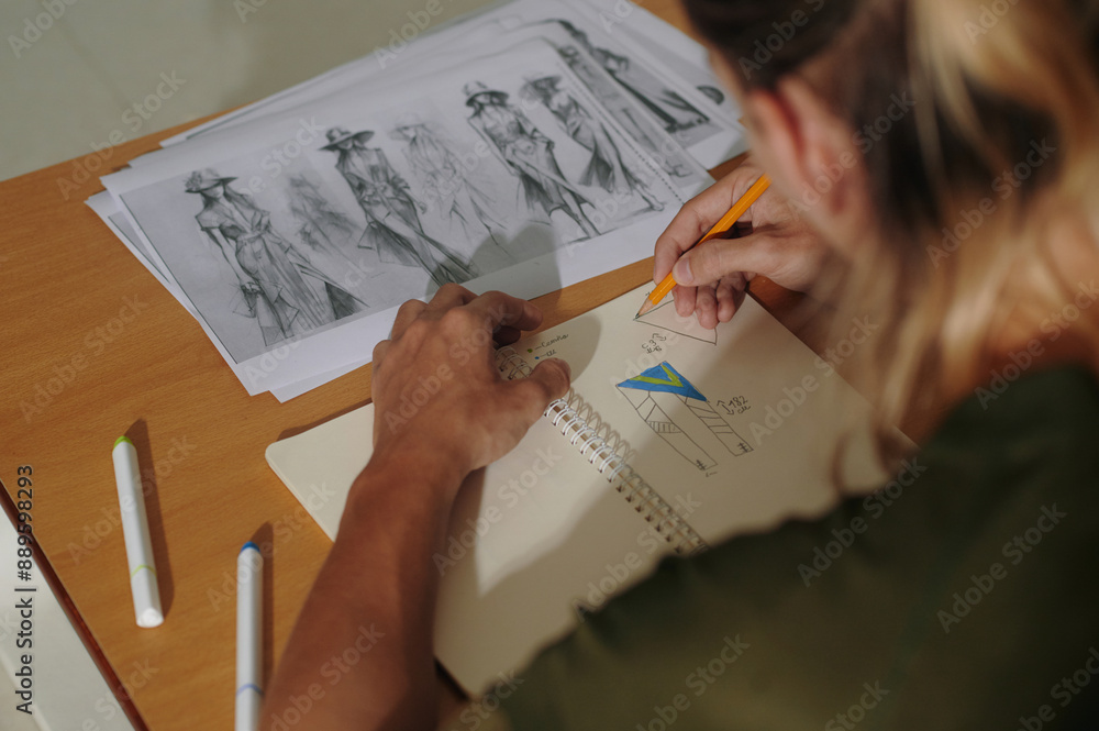 High angle view of designer working with his sketches at table High angle view of designer working with his sketches at table