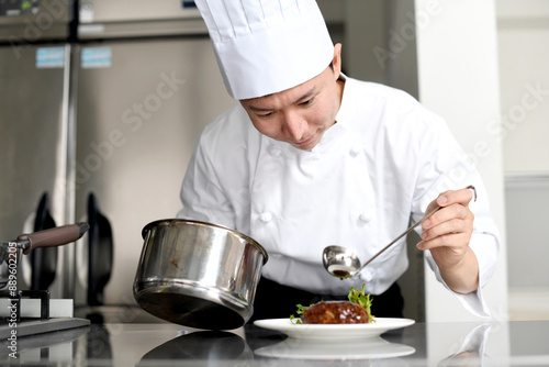 料理を皿に盛る若いアジア人の男性調理師