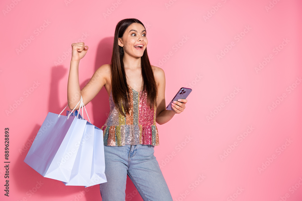 Photo of lucky lovely girl wear tank top holding shoppers making sale orders modern device empty space isolated pink color background Photo of lucky lovely girl wear tank top holding shoppers making sale orders modern device empty space isolated pink color background