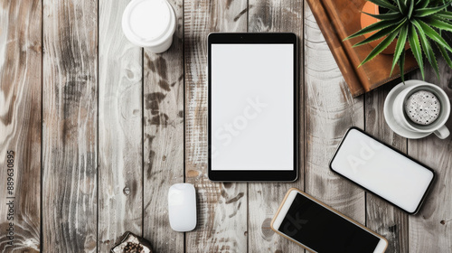 A tablet sits on a wooden table next to a mouse and two cell phones