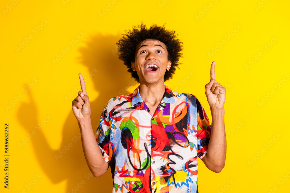 Portrait of nice young man indicate fingers up empty space wear shirt isolated on vivid yellow color background Portrait of nice young man indicate fingers up empty space wear shirt isolated on vivid yellow color background