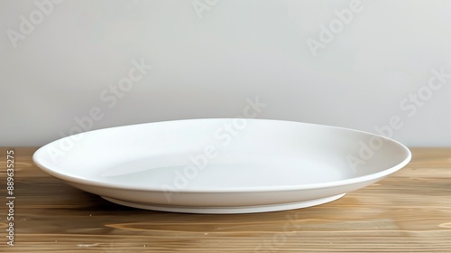 A white ceramic plate sits empty on a wooden table. © Farm