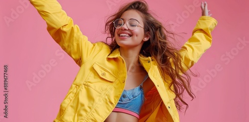 Smiling Woman Wearing a Yellow Jacket and Sunglasses Posing on Pink Background