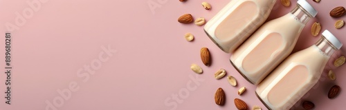 Three Bottles of Almond Milk on Pink Background With Almonds and Peanuts