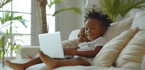 Young Boy Uses Laptop While Sitting On A Couch In A Sunny Room