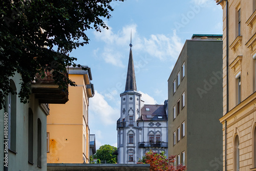 View of a historic building with a pointed tower between unadorned modern buildings in Augsburg photo