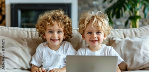 Two Young Boys Smiling at Laptop on a Couch in a Living Room