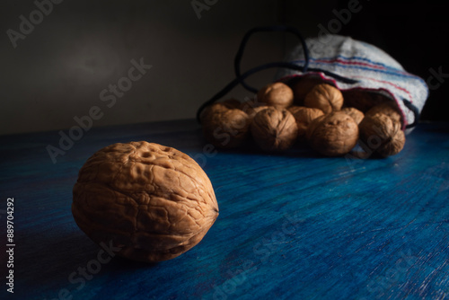 Comida. Nuez Chandler separada de una pequeña bolsa llena de nueces sobre mesa azul. photo